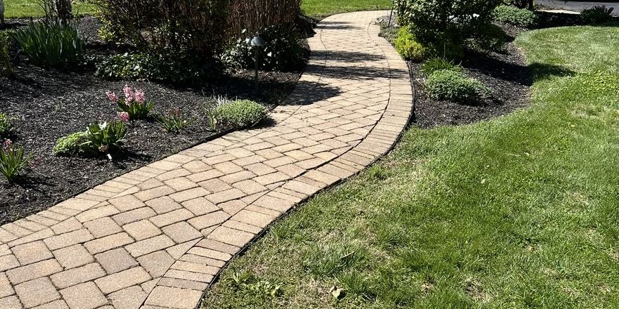 Clean brick paver walkway curving through planted beds